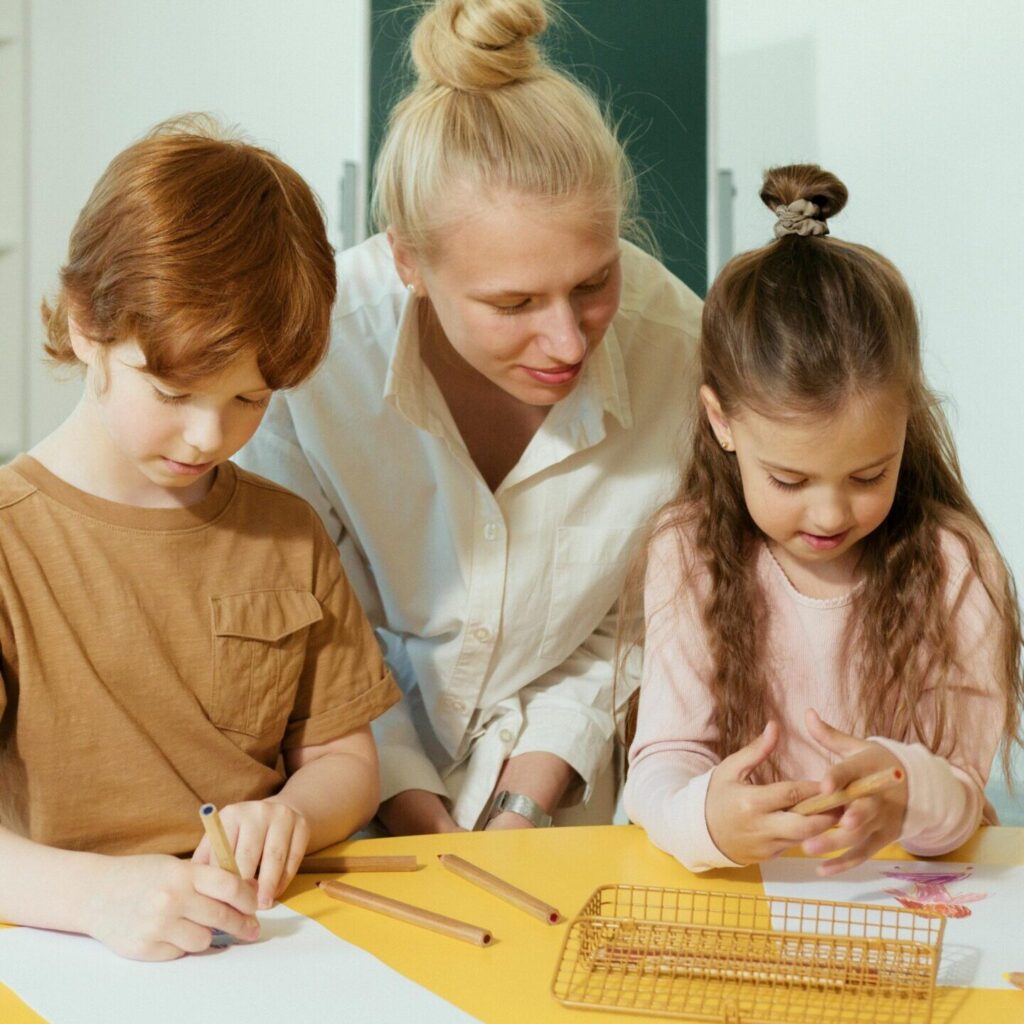 Teacher assists children in a classroom with learning activities.